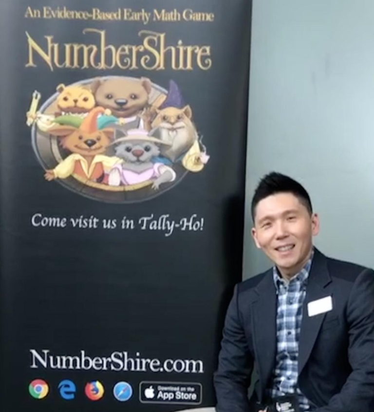 Sam Choo sitting next to a NumberShire banner